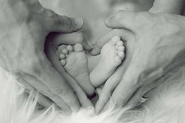 Eltern umranden Babyfüße als Herzform
